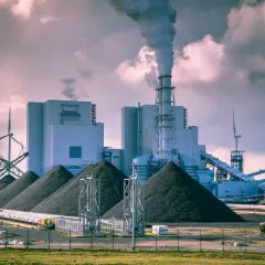 Ein Kohlekraftwerk mit rauchendem Schornstein, riesigen Kohlehaufen und Windrädern. Hier wird gezeigt, wie funktioniert ein Kohlekraftwerk.