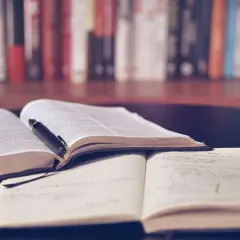 Offene Bücher und Notizhefte auf einem Tisch, bereit für das Lernen mit spaced repetition. Ein Stift liegt auf einem Buch.