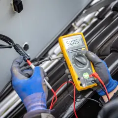 Ein Techniker misst mit einem Multimeter die Spannung an einem Solarmodul. Das Gerät zeigt 50,05 V an.