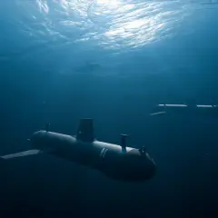 Mehrere U-Boote tauchen im tiefblauen Wasser auf, das Sonnenlicht bricht sich an der Oberfläche.