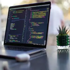 Ein Laptop zeigt Programmcode. Die Frage "wie lange braucht man um programmieren zu lernen" wird durch die vielen Zeilen Code visuell beantwortet.