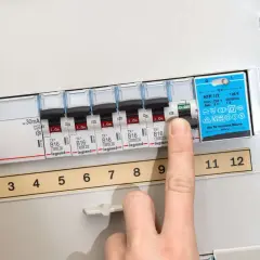Finger drückt auf Sicherungsschalter, um eine defekte Sicherung zu erkennen. Die Nummerierung der Schalter ist sichtbar.