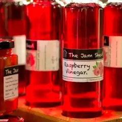 Rote Flaschen mit Himbeeressig von "The Jam Shed". Was ist Essig? Eine säuerliche Flüssigkeit, perfekt für Salate.