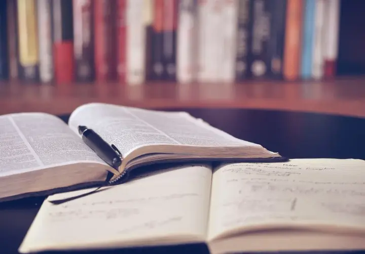 Offene Bücher und Notizhefte auf einem Tisch, bereit für das Lernen mit spaced repetition. Ein Stift liegt auf einem Buch.