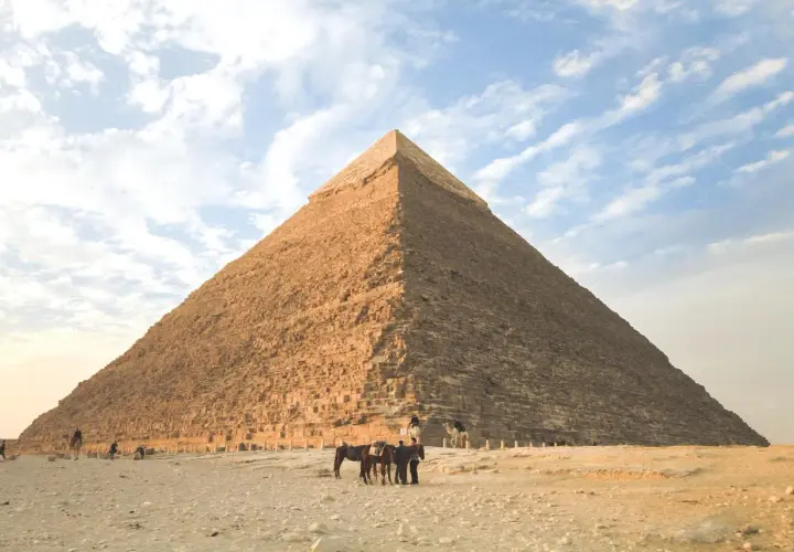 Die Pyramide von Gizeh, ein Meisterwerk geometrischer Formen im Alltag, ragt majestätisch in den Himmel. Menschen und Tiere beleben die Wüstenlandschaft.