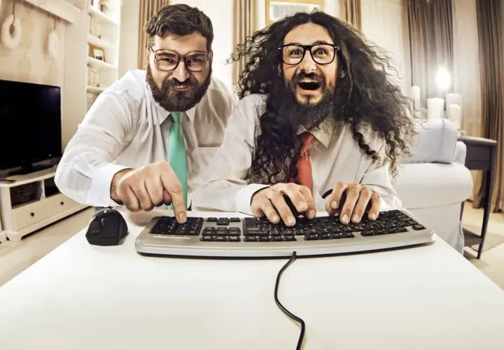 Zwei Männer mit Brillen und Krawatten tippen auf einer Tastatur.