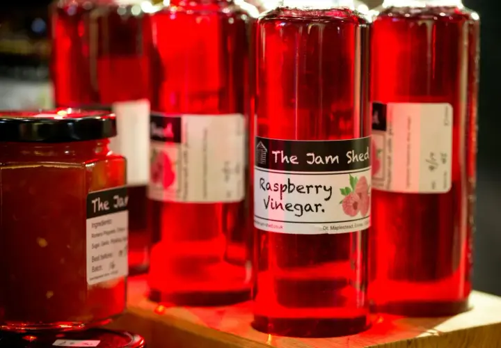 Rote Flaschen mit Himbeeressig von "The Jam Shed". Was ist Essig? Eine säuerliche Flüssigkeit, perfekt für Salate.