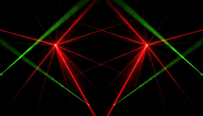 Rote und grüne Laserstrahlen kreuzen sich auf schwarzem Hintergrund. Das Bild zeigt, wie funktioniert ein laser, mit fokussierten Lichtpunkten und ausstrahlenden Strahlen.