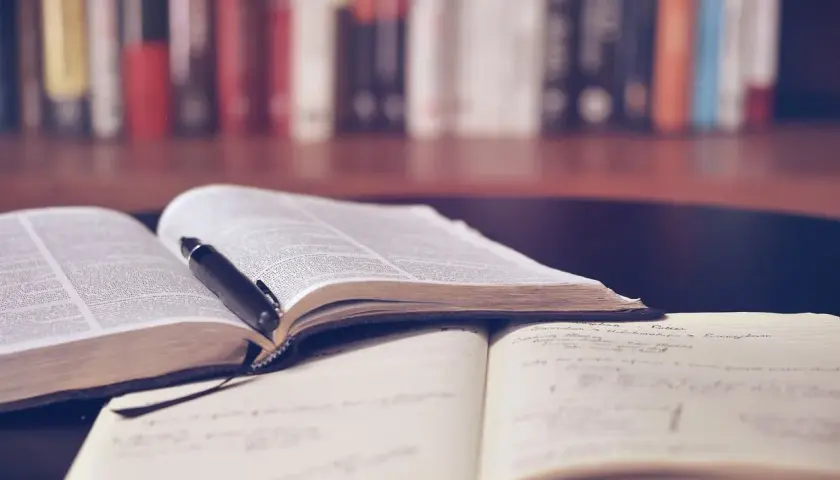 Offene Bücher und Notizhefte auf einem Tisch, bereit für das Lernen mit spaced repetition. Ein Stift liegt auf einem Buch.