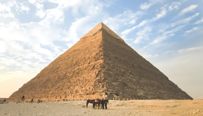 Die Pyramide von Gizeh, ein Meisterwerk geometrischer Formen im Alltag, ragt majestätisch in den Himmel. Menschen und Tiere beleben die Wüstenlandschaft.