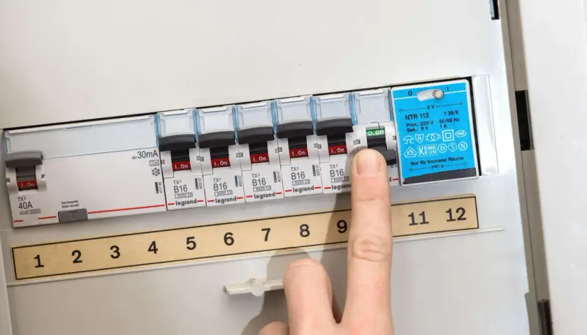 Finger drückt auf Sicherungsschalter, um eine defekte Sicherung zu erkennen. Die Nummerierung der Schalter ist sichtbar.