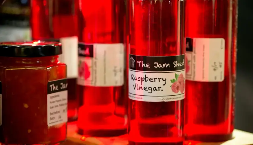 Rote Flaschen mit Himbeeressig von "The Jam Shed". Was ist Essig? Eine säuerliche Flüssigkeit, perfekt für Salate.
