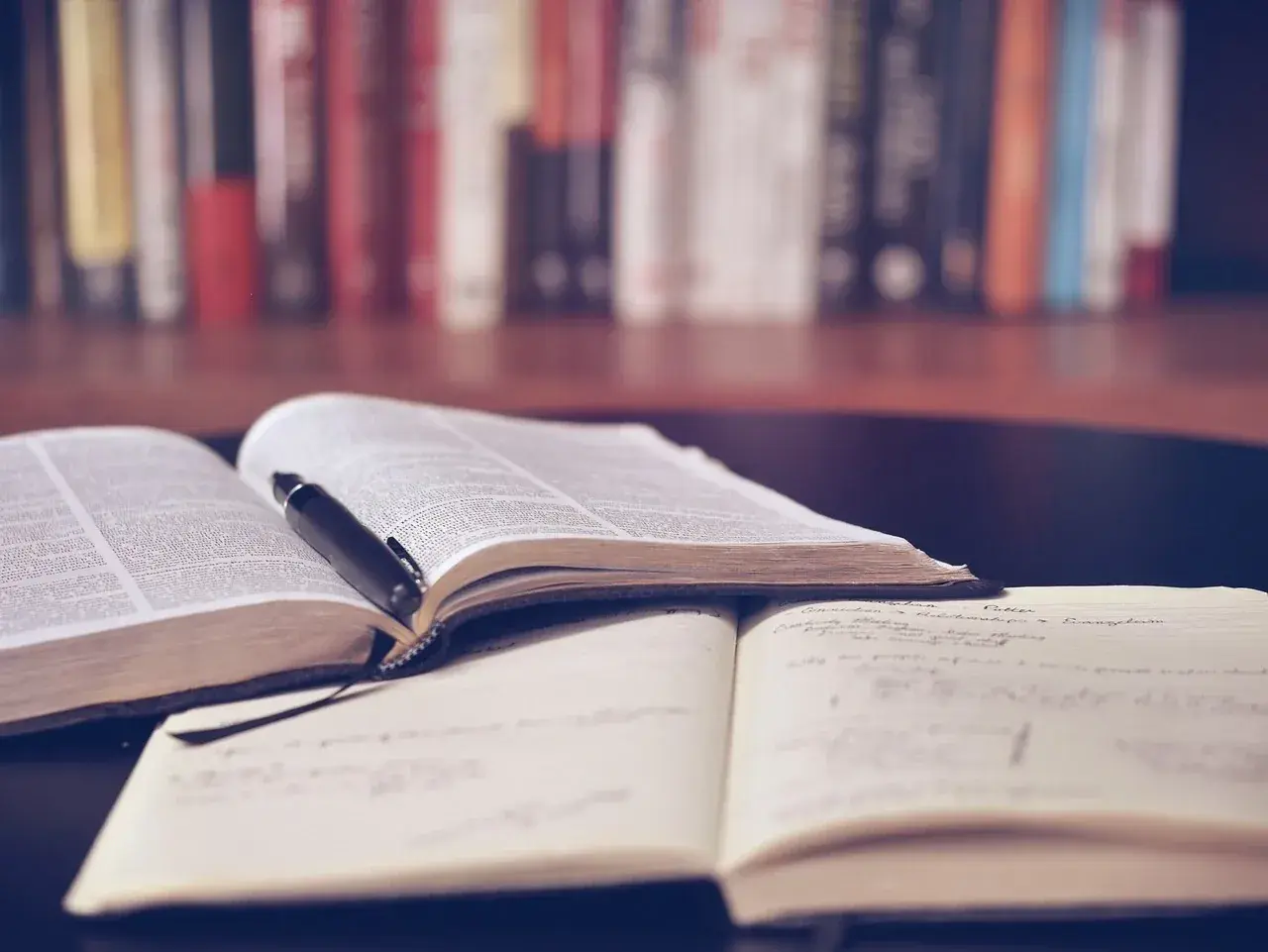 Offene Bücher und Notizhefte auf einem Tisch, bereit für das Lernen mit spaced repetition. Ein Stift liegt auf einem Buch.