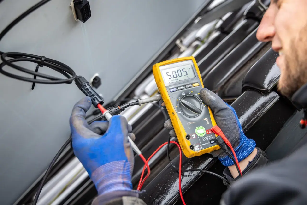 Ein Techniker misst mit einem Multimeter die Spannung an einem Solarmodul. Das Gerät zeigt 50,05 V an.