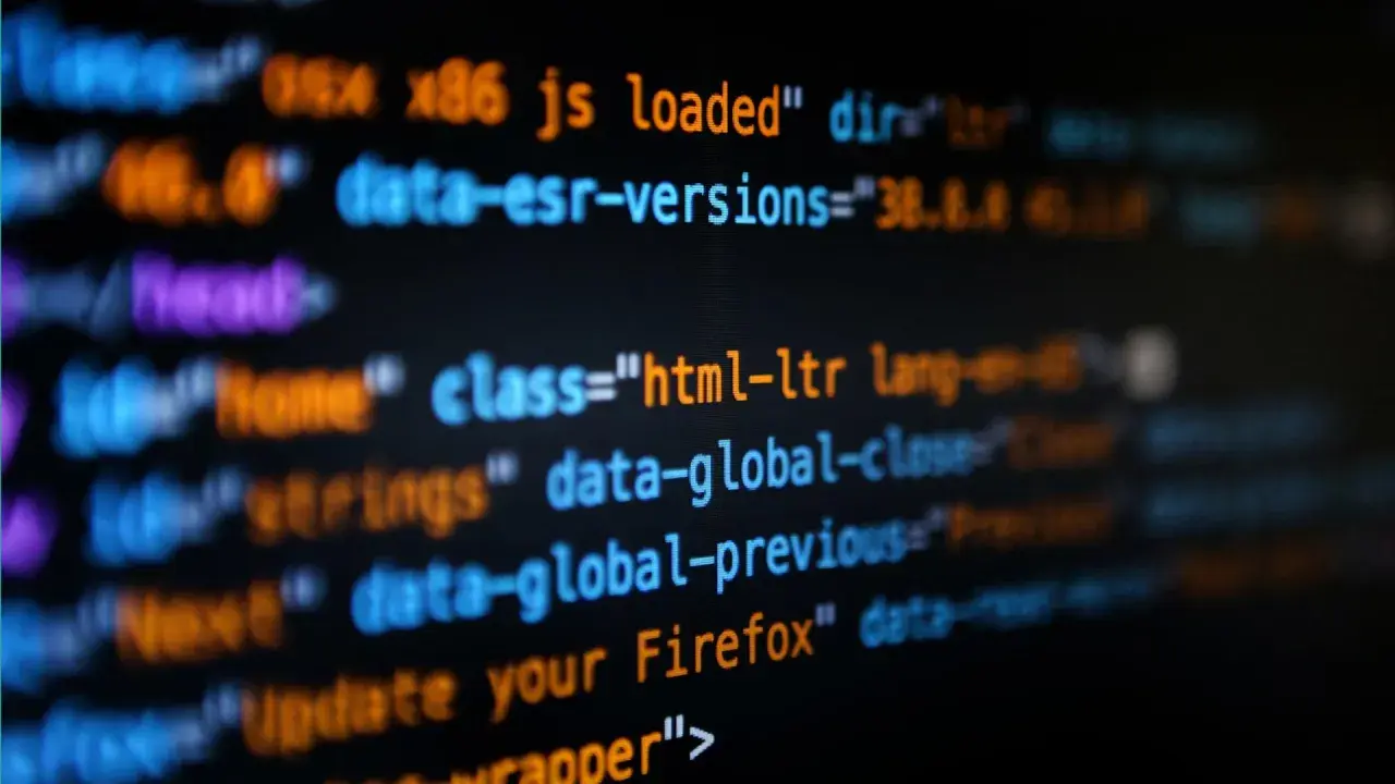 Bunte Codezeilen auf schwarzem Hintergrund. Hier siehst du, was ist coden: Befehle, die eine Webseite zum Leben erwecken, wie "html-ltr" oder "update your Firefox".