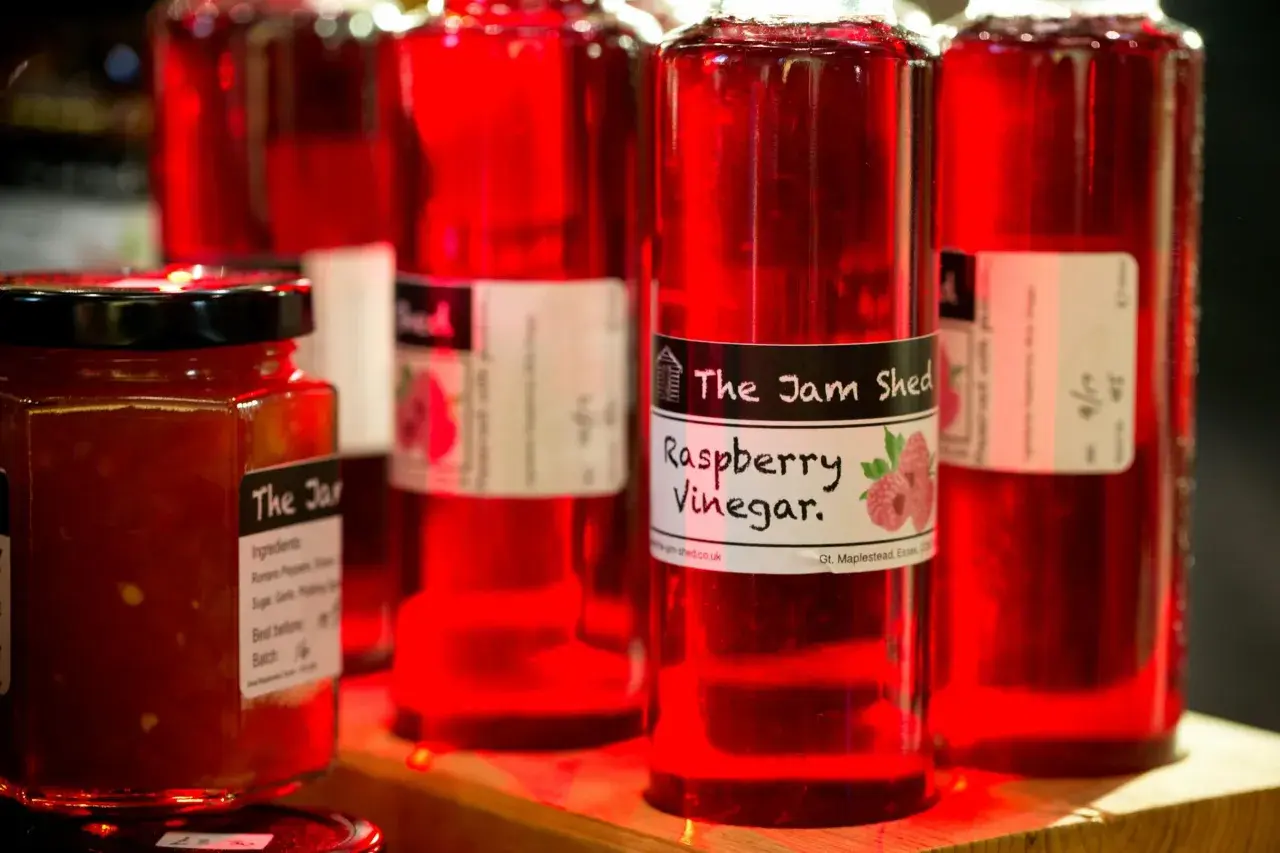 Rote Flaschen mit Himbeeressig von "The Jam Shed". Was ist Essig? Eine säuerliche Flüssigkeit, perfekt für Salate.