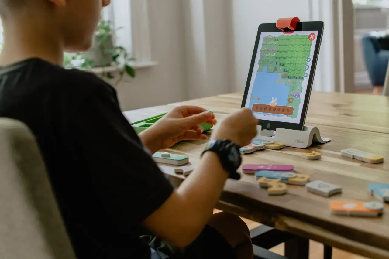 Kind lernt, was ist coding, indem es mit physischen Bl&ouml;cken auf einem Tablet programmiert.